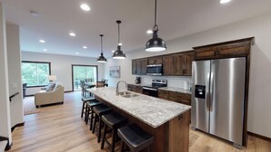 A modern kitchen with a central island, stainless steel appliances, and pendant lighting. - The Blue Ox on Gull, 5 Bed 5 Bath Resort Home, Sleeps 17 with Boat Slip on Gull Lake (Lake Shore)