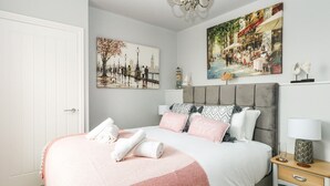 Una camera da letto ordinata con un letto, un comodino, una lampada e due quadri appesi al muro.