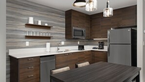 Eine moderne Küche mit dunklen Holzschränken, einer weißen Arbeitsplatte und Edelstahlgeräten.