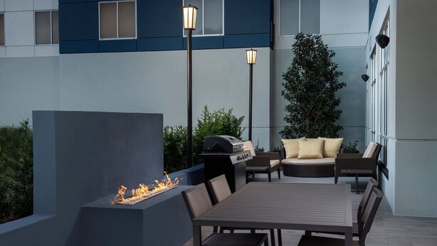 Eine Terrasse im Freien mit Feuerstelle, Sitzgelegenheiten und Grill.