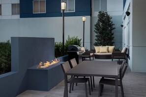Une terrasse extérieure dotée d’un foyer, de sièges et d’un barbecue.