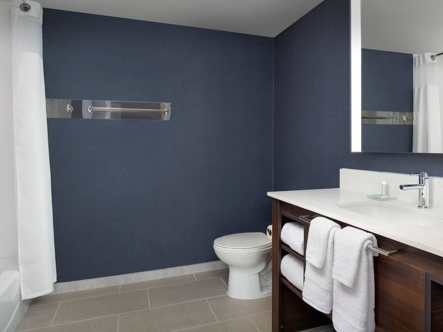 A modern bathroom with a white toilet, a sink with a mirror, and a towel rack.
