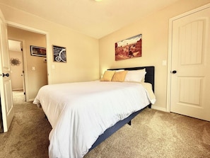A bedroom with a bed, a door, and a wall with a picture. - Kasa Kanab L6 - Townhome w/ Pool & Hot Tub (Kanab)