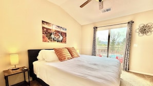 Hotelkamer met een bed, nachtkastje, lamp, plafondventilator, schilderij en uitzicht op de omgeving.