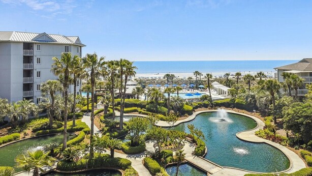 Un complexe hôtelier doté d’une piscine, de palmiers et offrant une vue sur la plage.