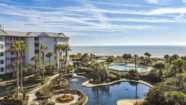 A resort with a pool area, palm trees, and a view of the ocean. - Luxury Oceanfront Villa w/ Views & Amenities (Hilton Head Island)