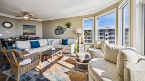 A spacious living room with a large sofa, a dining area, and a view of a building with balconies. - Luxury Oceanfront Villa w/ Views & Amenities (Hilton Head Island)