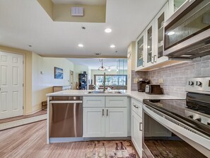 A modern kitchen with a central island, stainless steel appliances, and a view to the backyard.