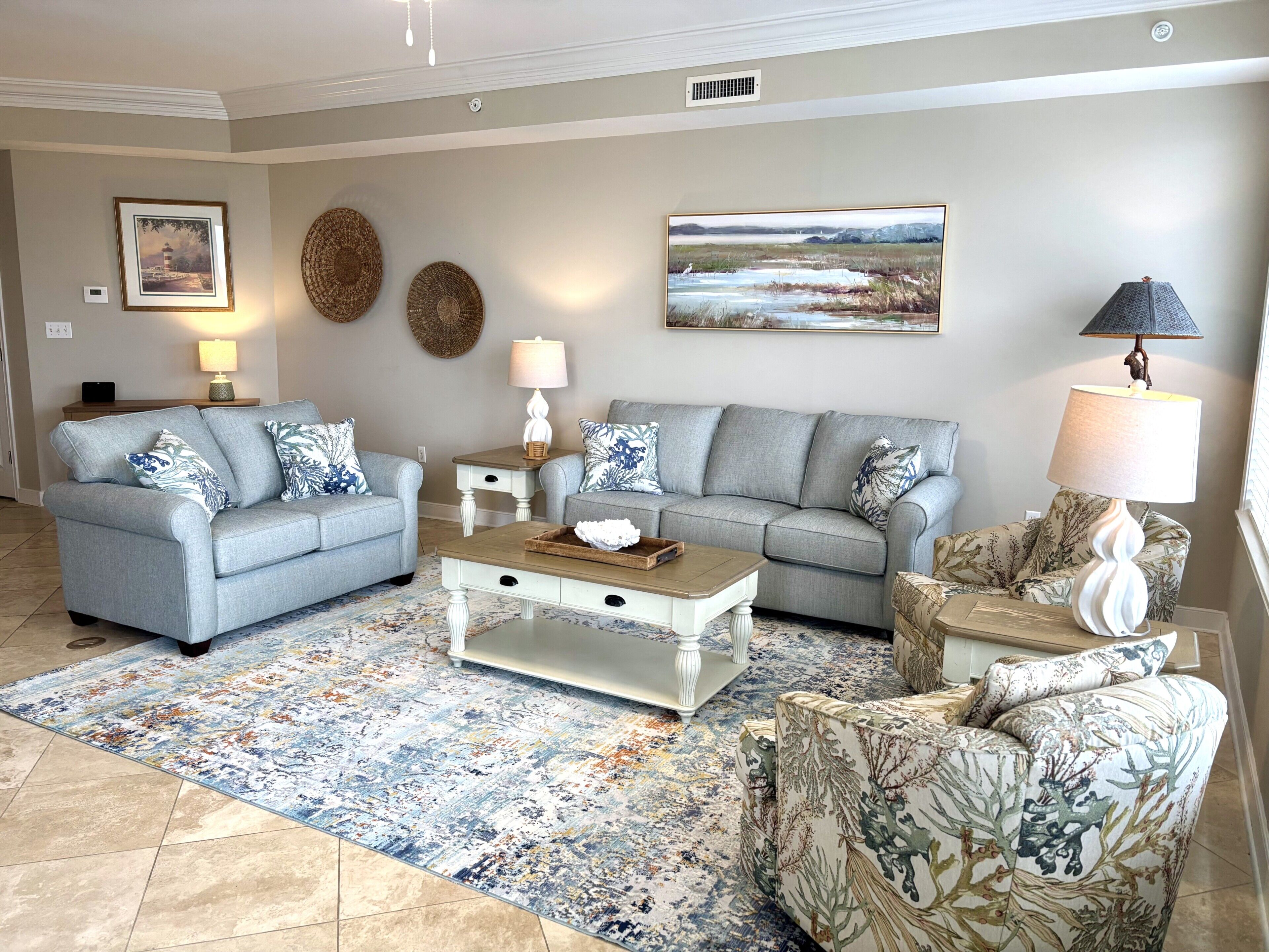 A living room with two grey sofas, a coffee table, a patterned rug, and wall art.