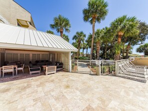 An outdoor patio with seating, a covered area, and palm trees.