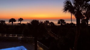 Ein Sonnenuntergang mit Blick von einem Resort, Palmen und einem Pool.