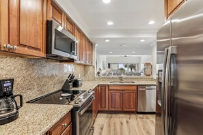 A modern kitchen with granite countertops, stainless steel appliances, wooden cabinets, and a built-in microwave. - Gorgeous Villa w/ Beautiful Views & Amenities (Hilton Head Island)