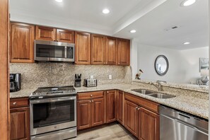 Una cocina moderna con armarios de madera, electrodomésticos de acero inoxidable, encimeras de granito y horno empotrado.