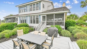 Une maison à deux étages dotée d’un patio couvert, d’un espace salon extérieur et d’une véranda grillagée.