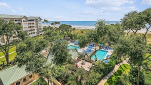 A resort with multiple swimming pools, a beach, and a large building with balconies.