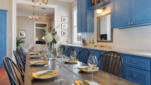 A dining area with a long wooden table set for a meal, blue cabinets, and a chandelier.
