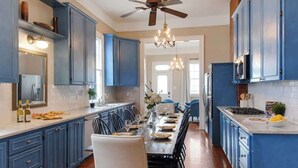 A kitchen with blue cabinets, a dining table set for six, and a chandelier.