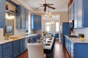 A kitchen with blue cabinets, a dining table set for six, and a chandelier.