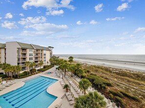 A hotel with a swimming pool, beach view, and multiple balconies.