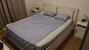 Una habitación de hotel estándar con una cama individual, una mesita de noche, una lámpara y una pequeña mesa con lámpara.