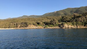 Paisaje costero con cielo despejado, una masa de agua y montañas al fondo.