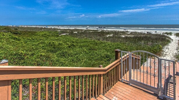 A wooden deck with a metal railing overlooking a beach with sand dunes and a clear blue sky. - 3BR Villa w/ Just a 2 Minute Walk from Beach (Hilton Head Island)