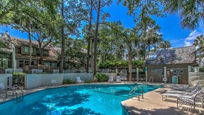 A swimming pool surrounded by trees and lounge chairs, with a lifeguard station nearby. - 3BR Villa w/ Just a 2 Minute Walk from Beach (Hilton Head Island)