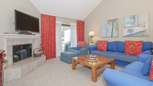 A living room with a fireplace, a sofa set, a television, and a ceiling fan. - 3BR Villa w/ Just a 2 Minute Walk from Beach (Hilton Head Island)