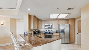 Una cocina moderna con encimeras de granito, electrodomésticos de acero inoxidable y armarios de madera.