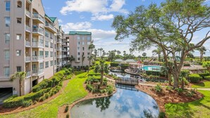 Un hotel con varias plantas, piscinas al aire libre y exuberante jardinería.