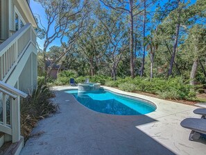Piscina con jacuzzi, rodeada de árboles y una zona de patio.