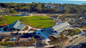 Vue aérienne d’un terrain de golf avec un club-house, un parking et des immeubles résidentiels environnants.