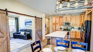 A spacious kitchen with wooden cabinets, a central island, and modern appliances. - Shepherd Family Retreats- Bear Cub: 2BR, 2BA home 6 min from Yellowstone National Park (West Yellowstone)