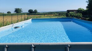 A clear blue swimming pool with a view of a vineyard and distant hills. - The house in the fields_Dépendance (Lombardia)
