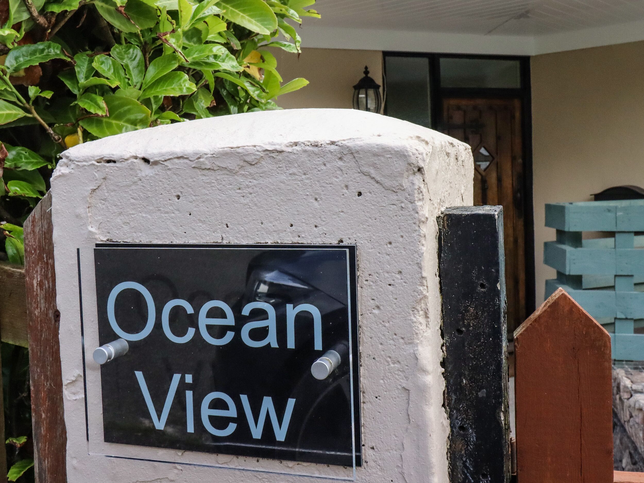 Un cartello con la scritta 'Ocean View' fissato a una parete dalla superficie irregolare.