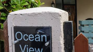 Un cartello con la scritta 'Ocean View' fissato a una parete dalla superficie irregolare.