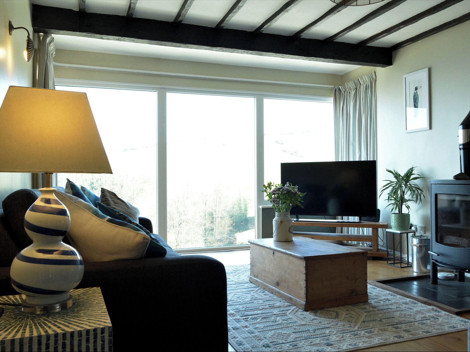 A living room with a sofa, a lamp, a television, a plant, and a fireplace.