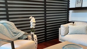 A modern living room with a sofa, a chair, a glass bowl on a table, and a decorative plant.