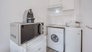 A compact kitchen with a microwave, a washing machine, and a sink.