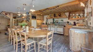 Eine rustikale Küche mit Holzschränken, einer zentralen Kochinsel und einem Essbereich mit Holztisch und Stühlen.