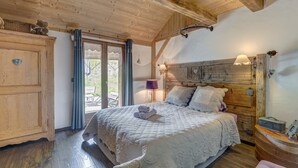 Ein Schlafzimmer mit Holzboden, einem Bett, einer Kommode und einem Fenster mit Vorhängen.