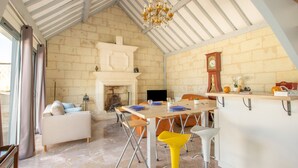 Une pièce spacieuse avec un plafond haut, une cheminée, une table à manger avec des chaises et un canapé.