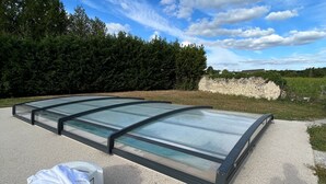 Un vaste espace extérieur, entièrement vitré, doté d’un sol en gravier et entouré d’arbres et d’un mur de pierre.