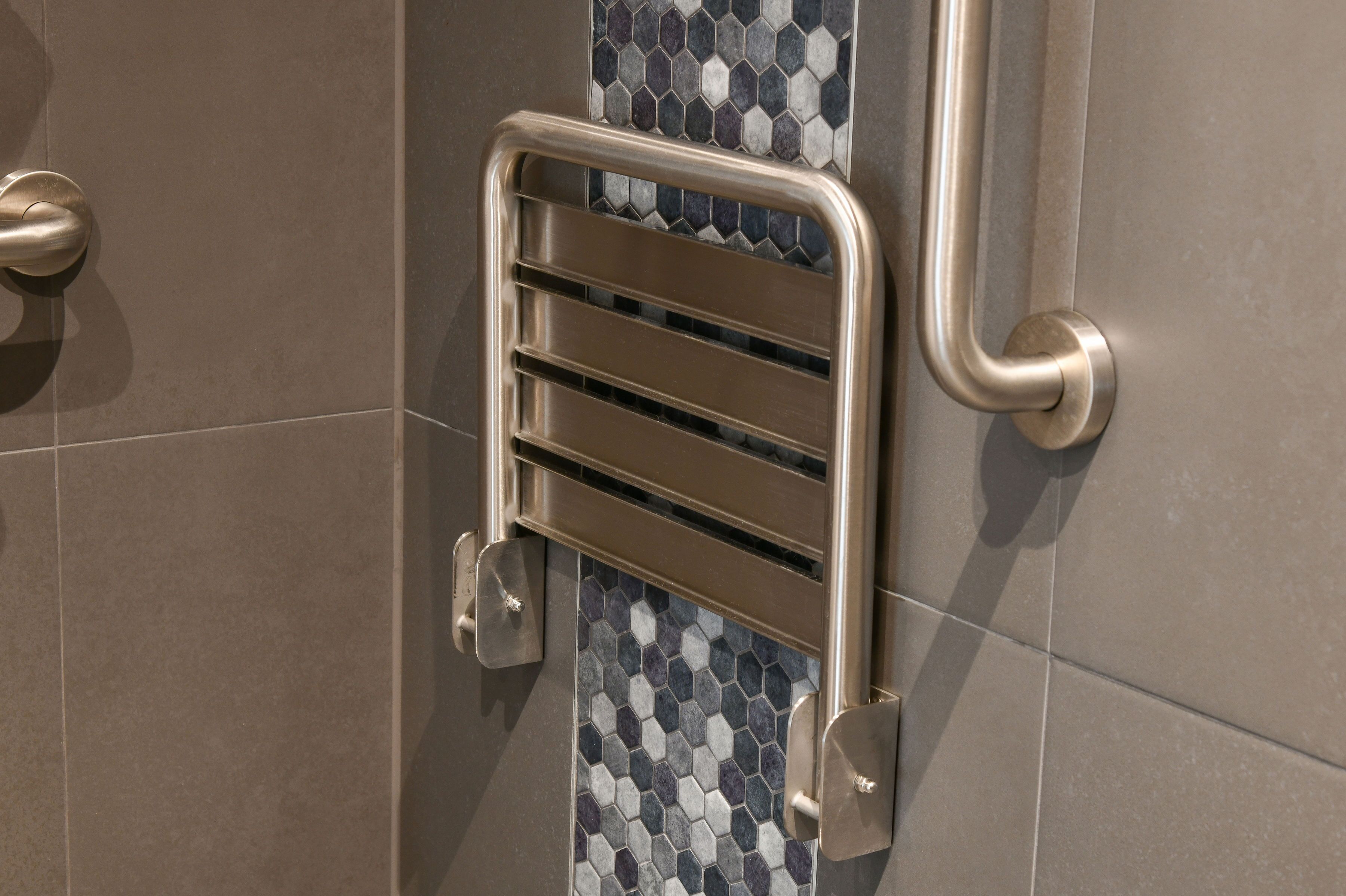 A bathroom with a handrail, tiled walls, and a door.