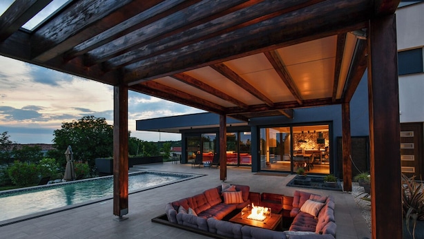 A modern outdoor living area with a fire pit, seating, and a pool.