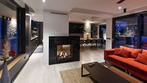 A modern living room with a fireplace, a sofa, and a dining area with a table and chairs.