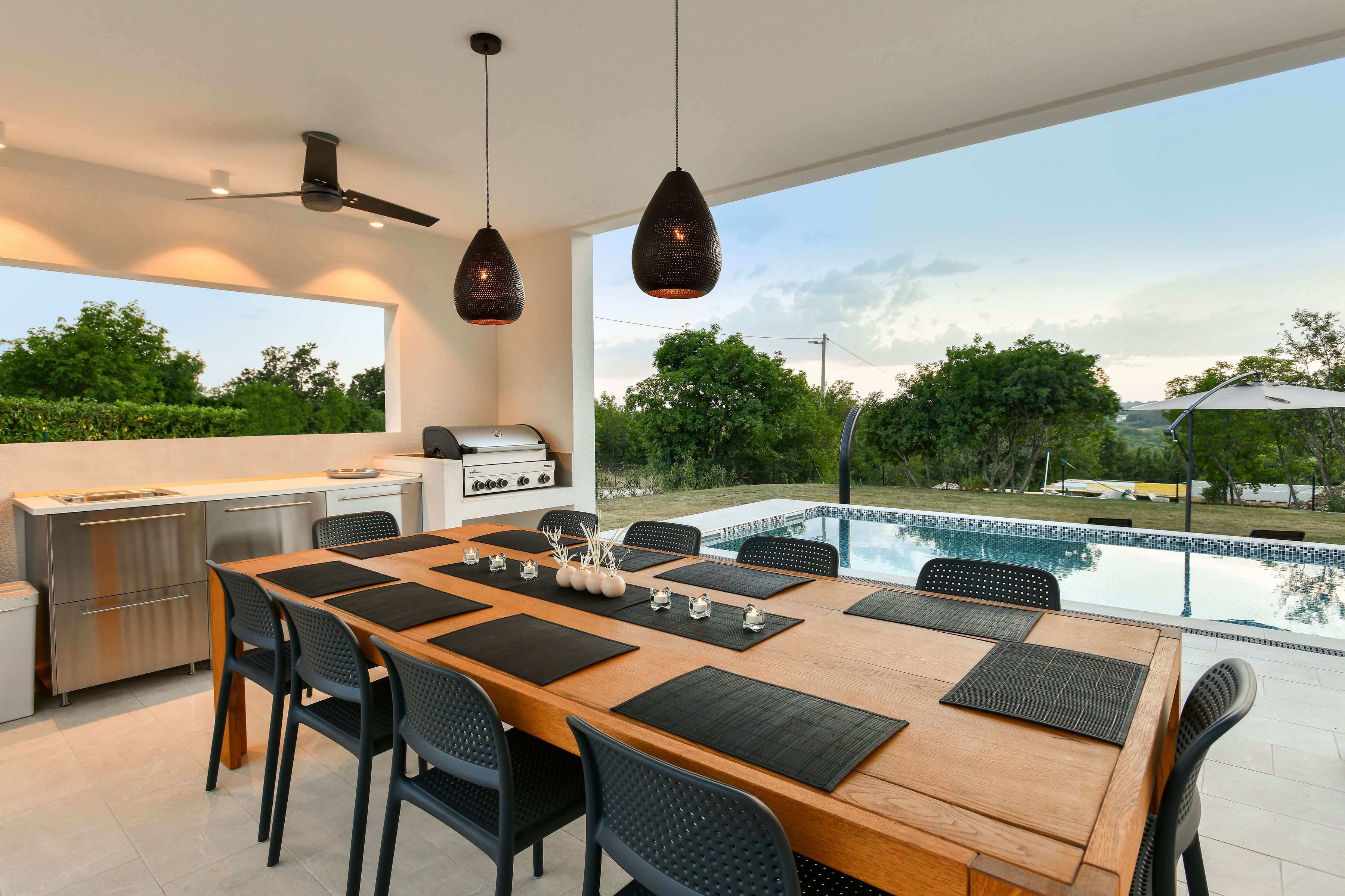 A modern kitchen with a dining area overlooking a swimming pool.