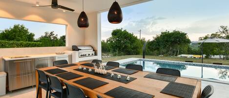 A modern kitchen with a dining area overlooking a swimming pool.