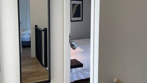 A bedroom with a bed, a bedside table, a framed picture on the wall, and a mirror on the wall. - Raaff-71 sfeervol huis direct bij bos, duin en strand (Noordwijk)