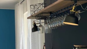 A modern kitchen with a wooden countertop, bar stools, and a wine rack with glasses. - Raaff-71 sfeervol huis direct bij bos, duin en strand (Noordwijk)